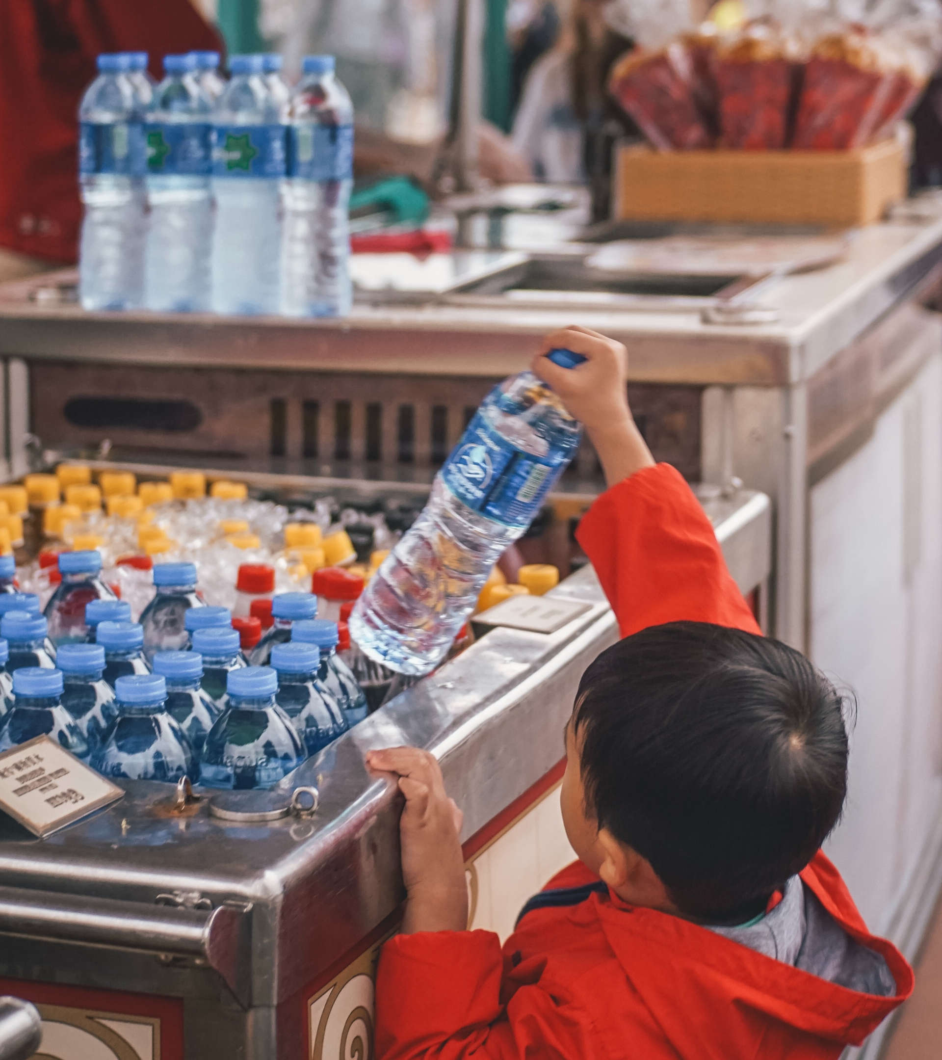 a child picking a PET water bottle out of a cooler